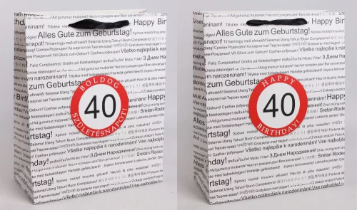 PAPÍRTASAK MATT, SZALAG FÜLLEL, FEHÉR ALAPON FEKETE, TÖBBFÉLE NEMZETKÖZI NYELVEN HAPPY BIRTHDAY FELIRATTAL A HÁTTÉRBEN, PIROS KARIKÁBAN ÉVSZÁMMAL, 40