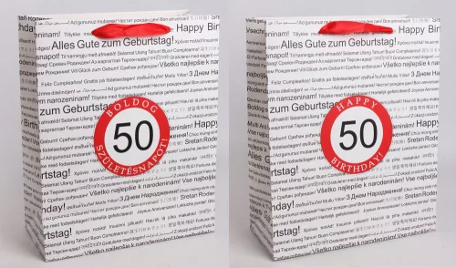 PAPÍRTASAK MATT, SZALAG FÜLLEL, FEHÉR ALAPON FEKETE, TÖBBFÉLE NEMZETKÖZI NYELVEN HAPPY BIRTHDAY FELIRATTAL A HÁTTÉRBEN, PIROS KARIKÁBAN ÉVSZÁMMAL, 50